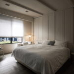 Dormitorio moderno decorado a partir de un estilo minimalista, una gran cama en el centro y unos estores para habitaciones blancos que cuelgan del techo